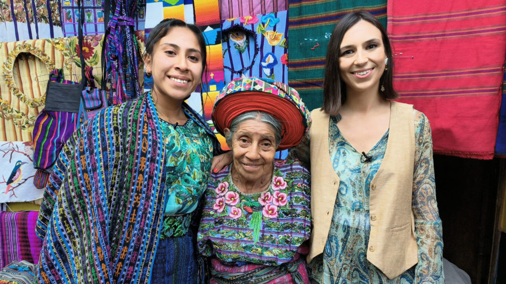 Veronica junto a dos mujeres guatemaltecas sonrientes que orgullosamente muestran la cultura de Guatemala.